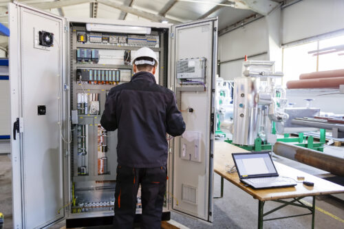 Man worker checking advanced industrial control panel in the production hall